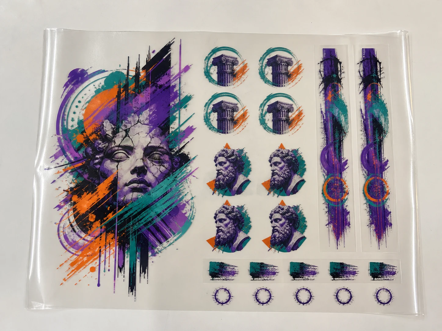 Illustrative overhead product mockup showing several artwork sizes arranged on clear DTF transfer film