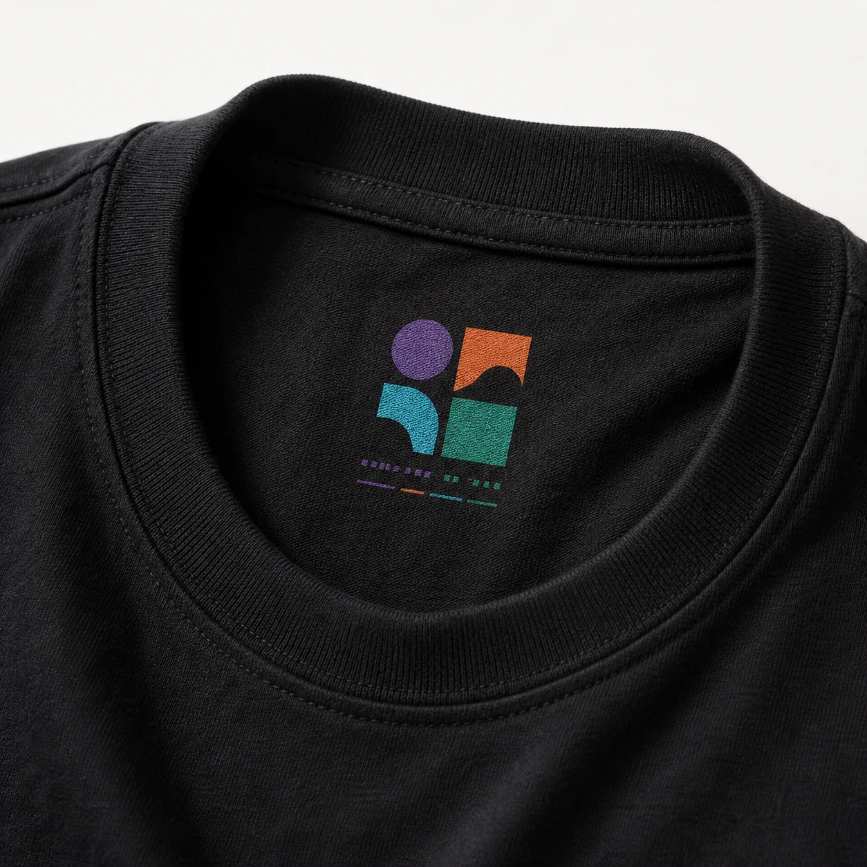 Illustrative close-up mockup of a black T-shirt collar with a small colorful printed label inside the neck